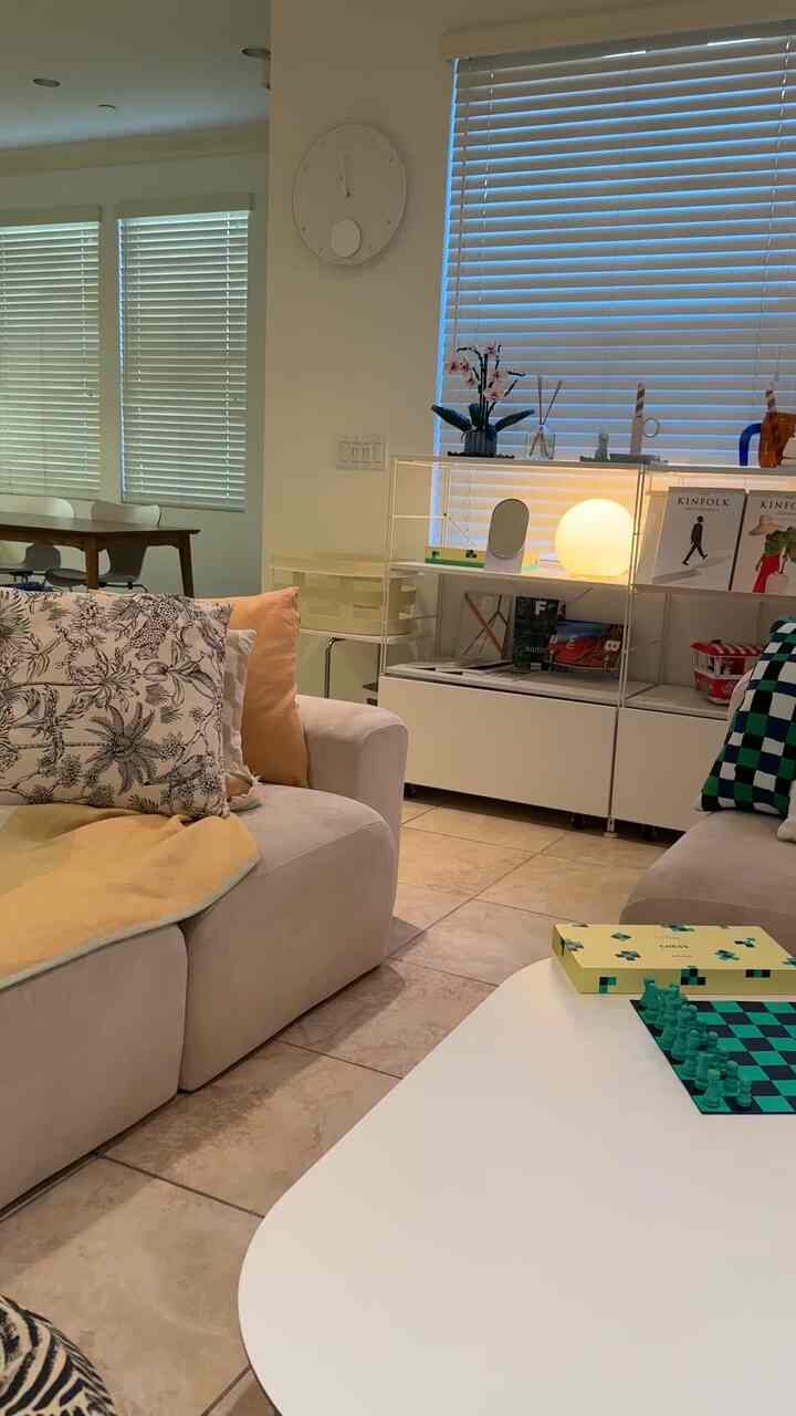 A white and beige toned living room featuring Mid-Century Modern sofa, coffee table with chess set creating a cozy atmosphere