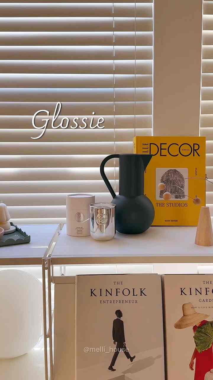 Modern living room with white and black tones, featuring candles and a jug on a bookshelf and shelf with a cozy atmosphere