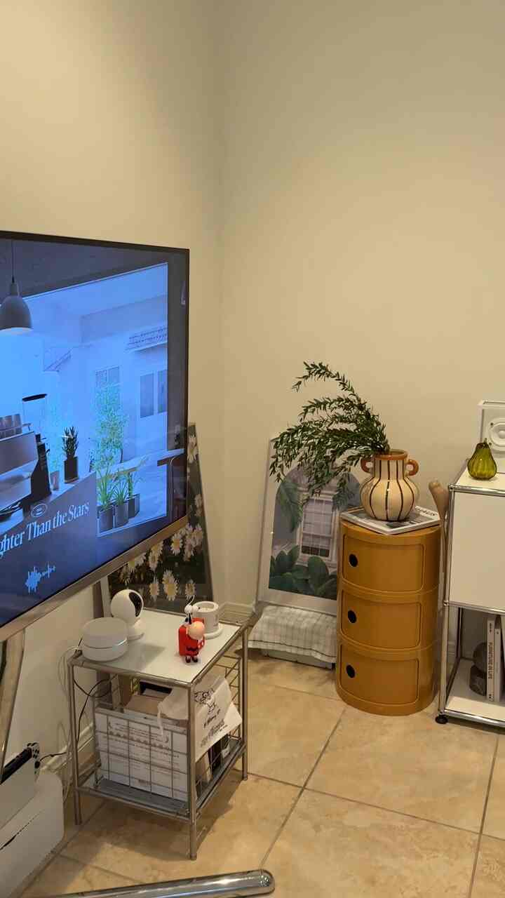 Modern living room with white walls, beige tiled floor, featuring side table and decorative plant