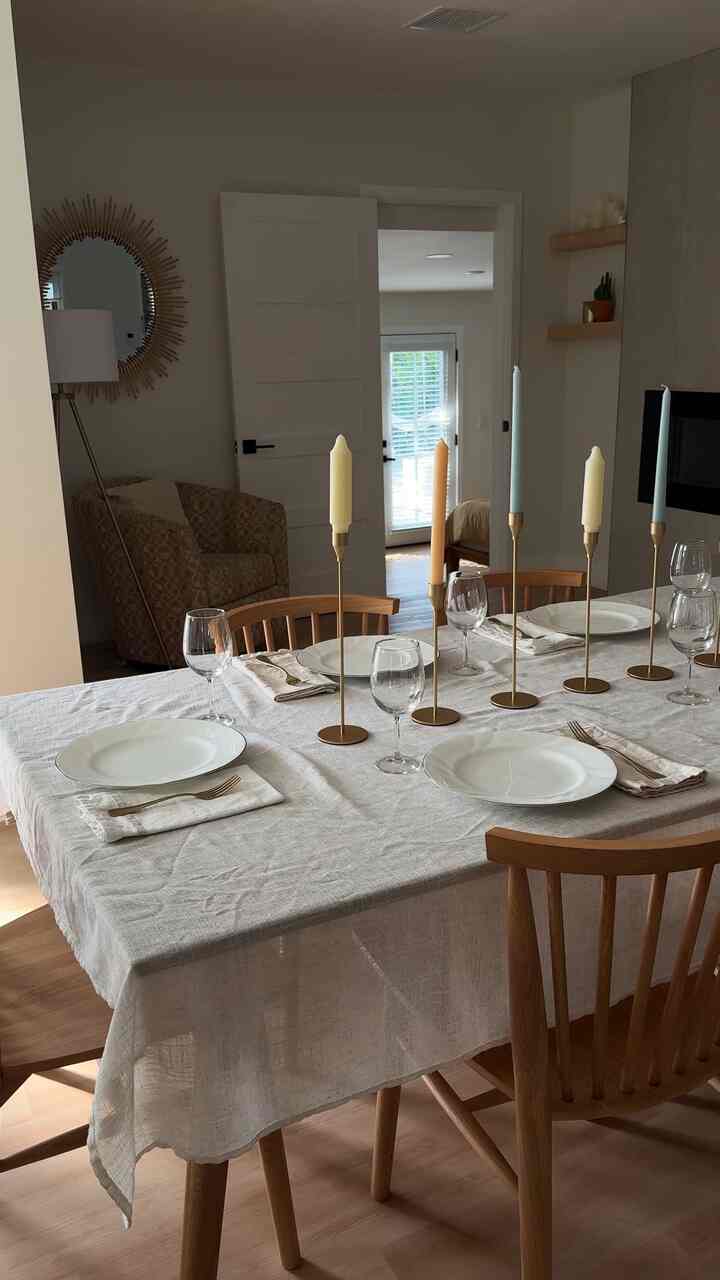 Natural wood tone and white dining room featuring a candlelit table and clean, stylish atmosphere