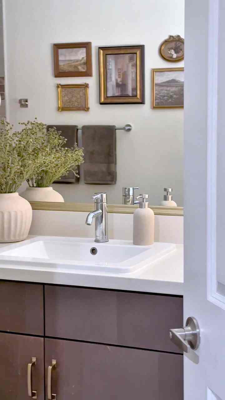 White and brown toned bathroom featuring a sink and vintage framed gallery wall creating a warm atmosphere