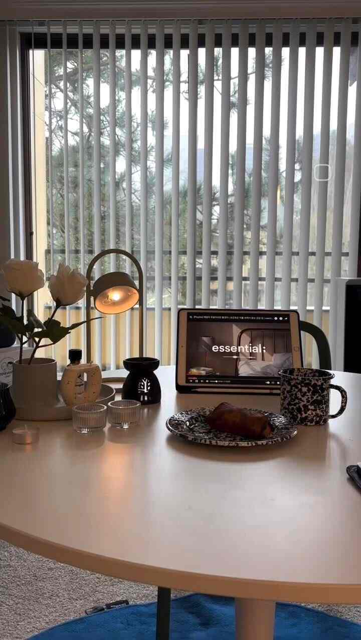 White-toned dining room with a round dining table featuring aroma oil burner, candle, and coffee cup creating a cozy atmosphere
