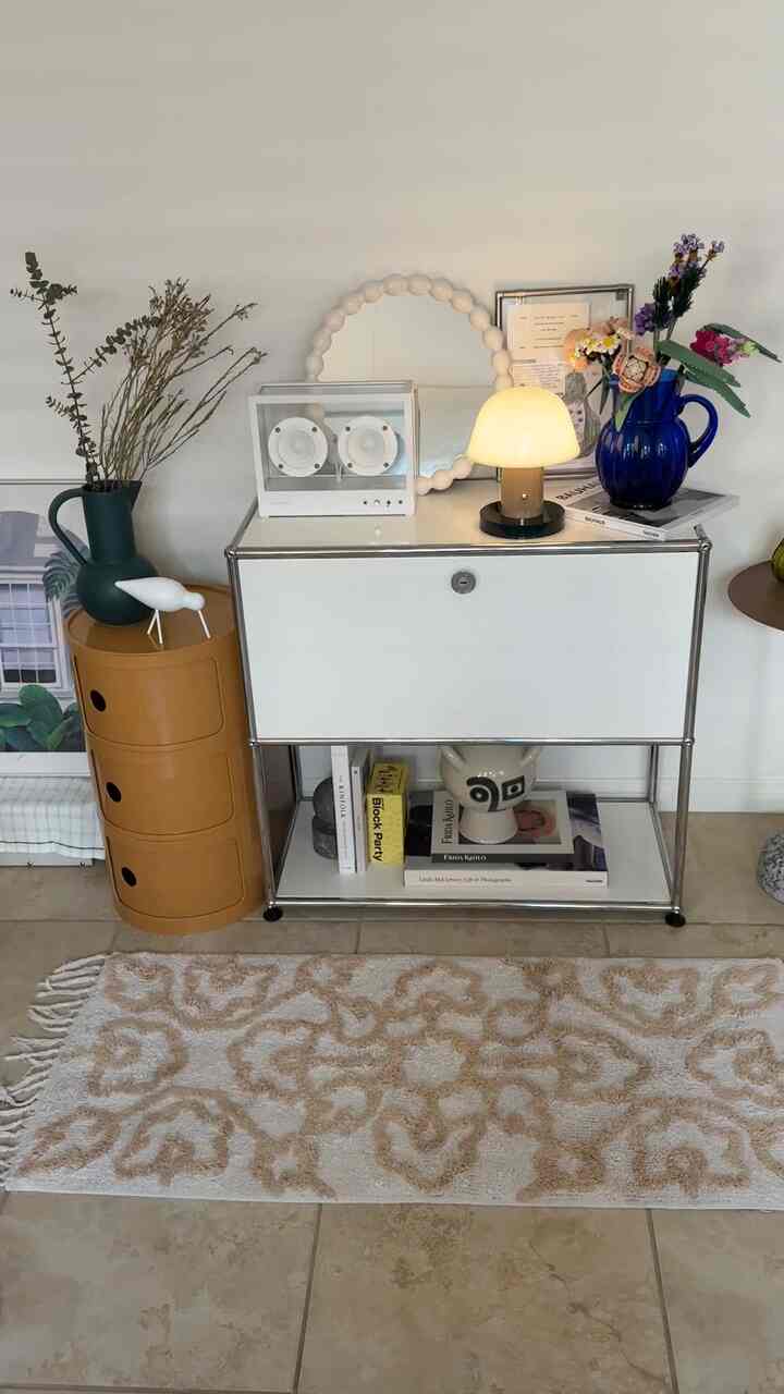 Mid-Century Modern living room in white and brown tones featuring a storage cabinet, side table with lighting and decorative elements creating a cozy atmosphere