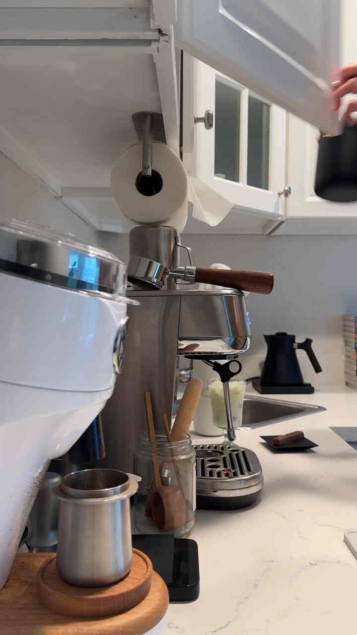Natural style home cafe kitchen featuring white cabinetry, stainless steel espresso machine, and wooden coffee utensils