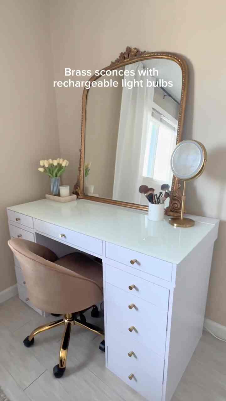 Natural color walls with white vanity featuring gold accents and wall sconces in elegant powder room