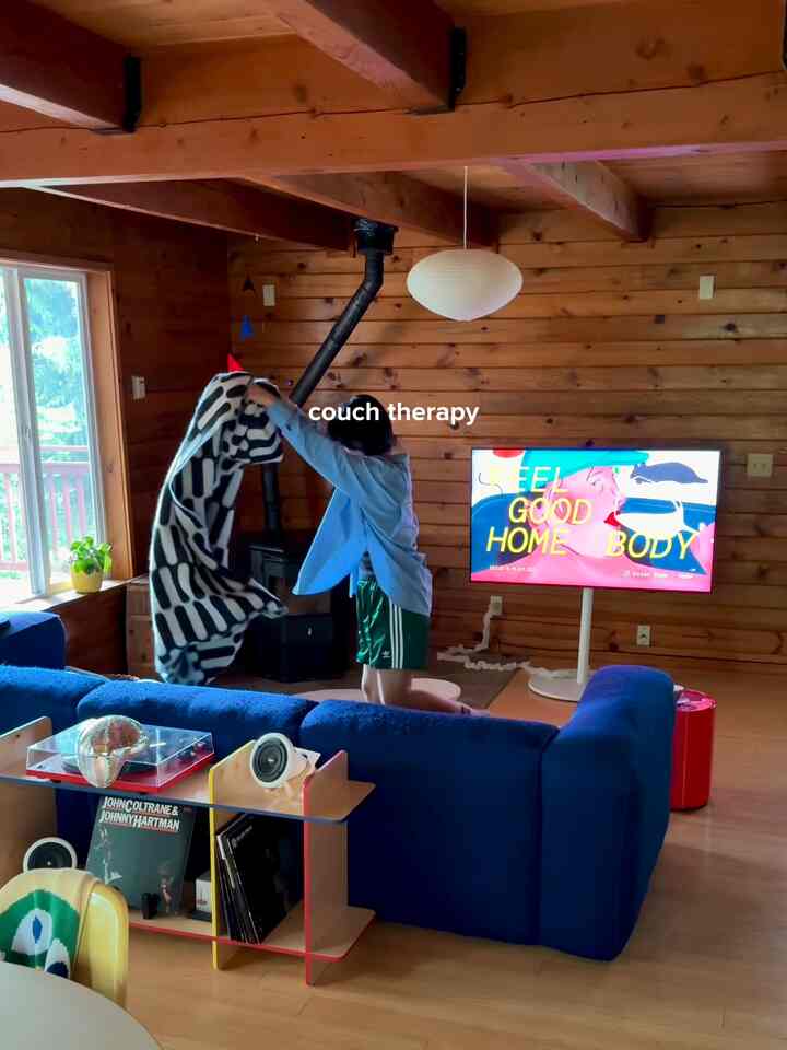 Cozy single household living room with natural wooden walls and a vivid blue sofa under exposed beams