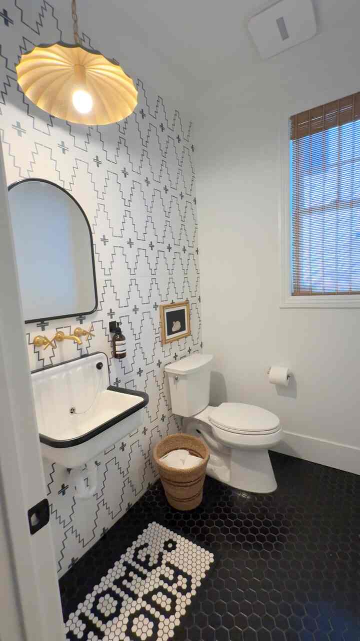 Monotone powder room in white and black featuring geometric patterned wall, pendant light, and modern fixtures