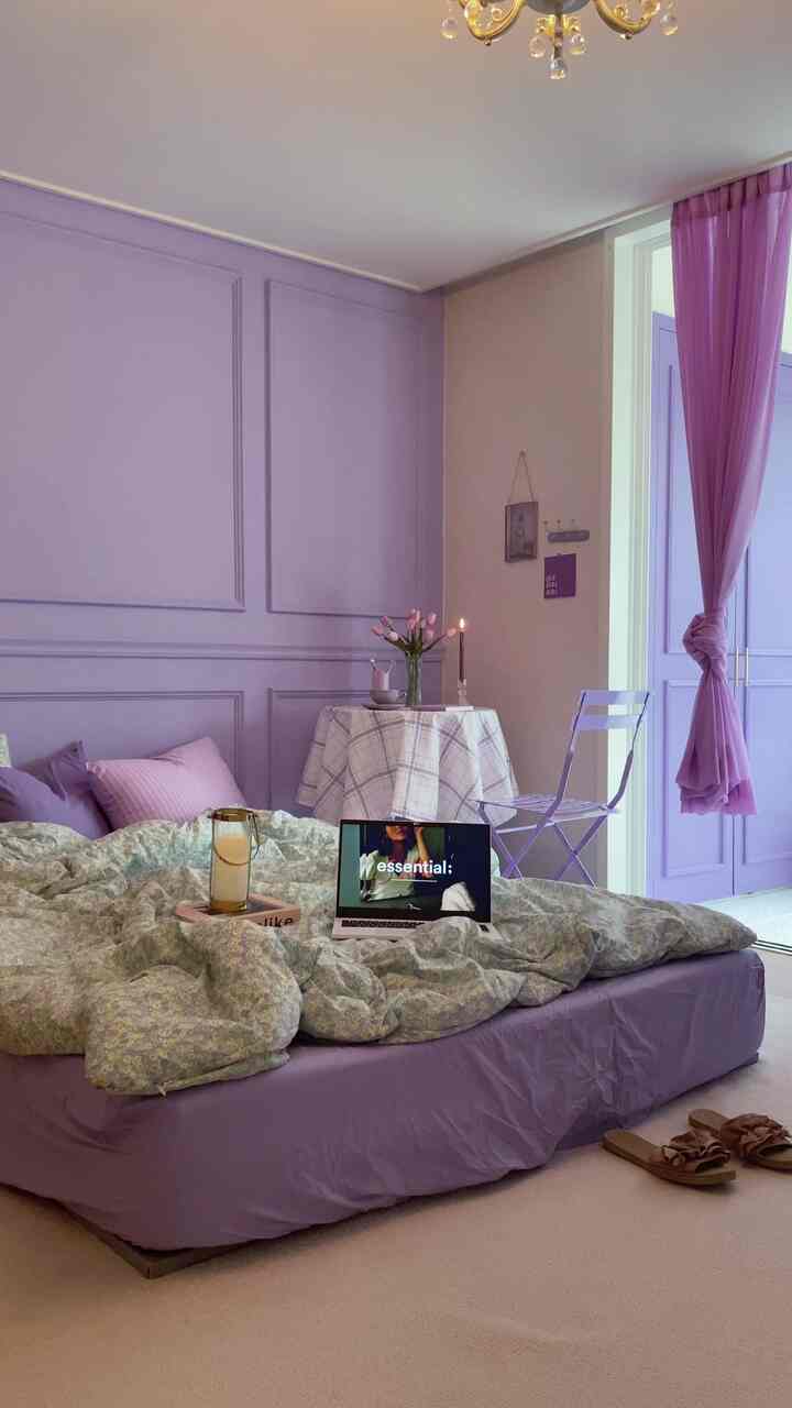 Soft purple-toned bedroom featuring a purple bed, curtain, and a small round table creating a cozy atmosphere