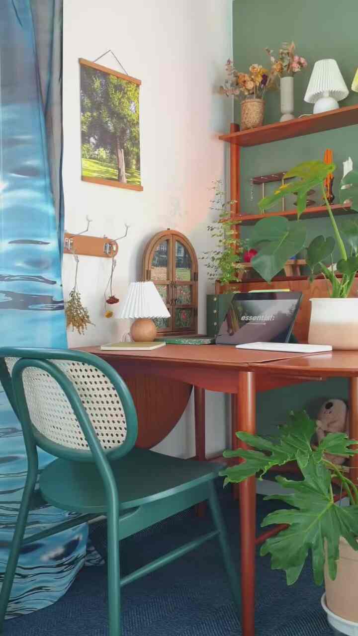 Natural modern home office featuring green walls, plants, and wooden furniture creating a cozy workspace