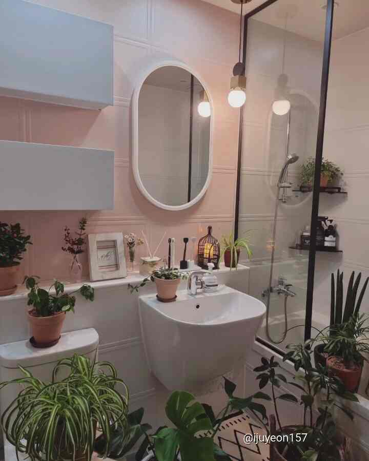 Pink and white toned bathroom featuring various plants and accessories with a cozy modern atmosphere