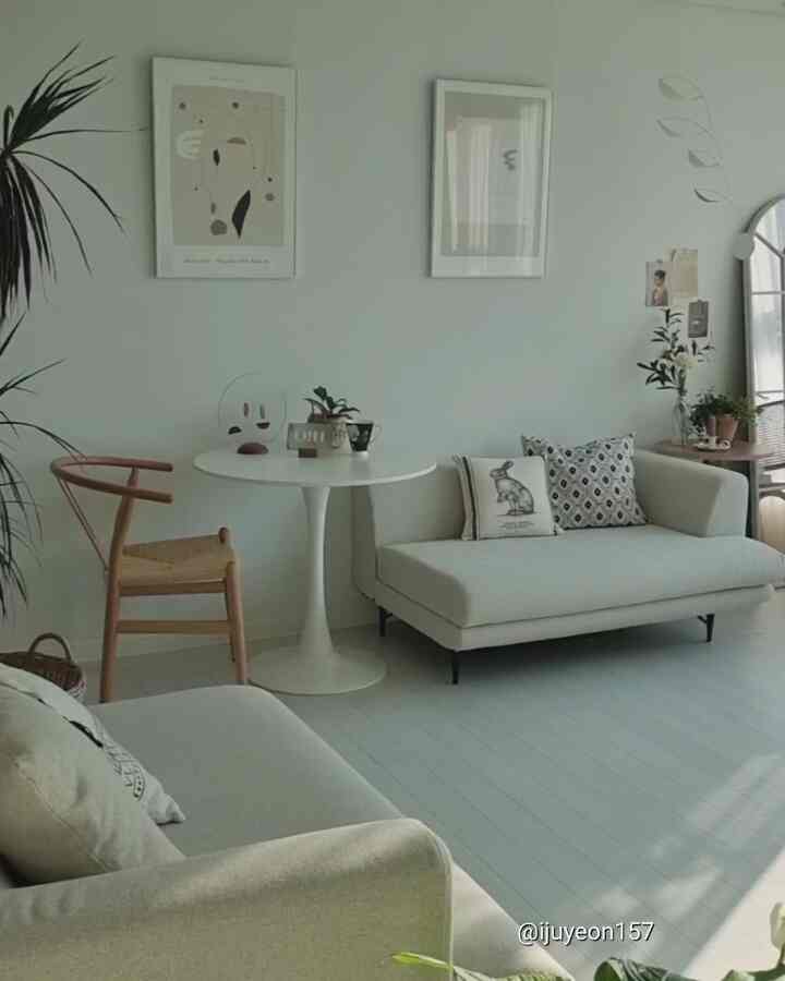 White and natural toned living room featuring sofas, round table, and rattan chair creating a cozy atmosphere