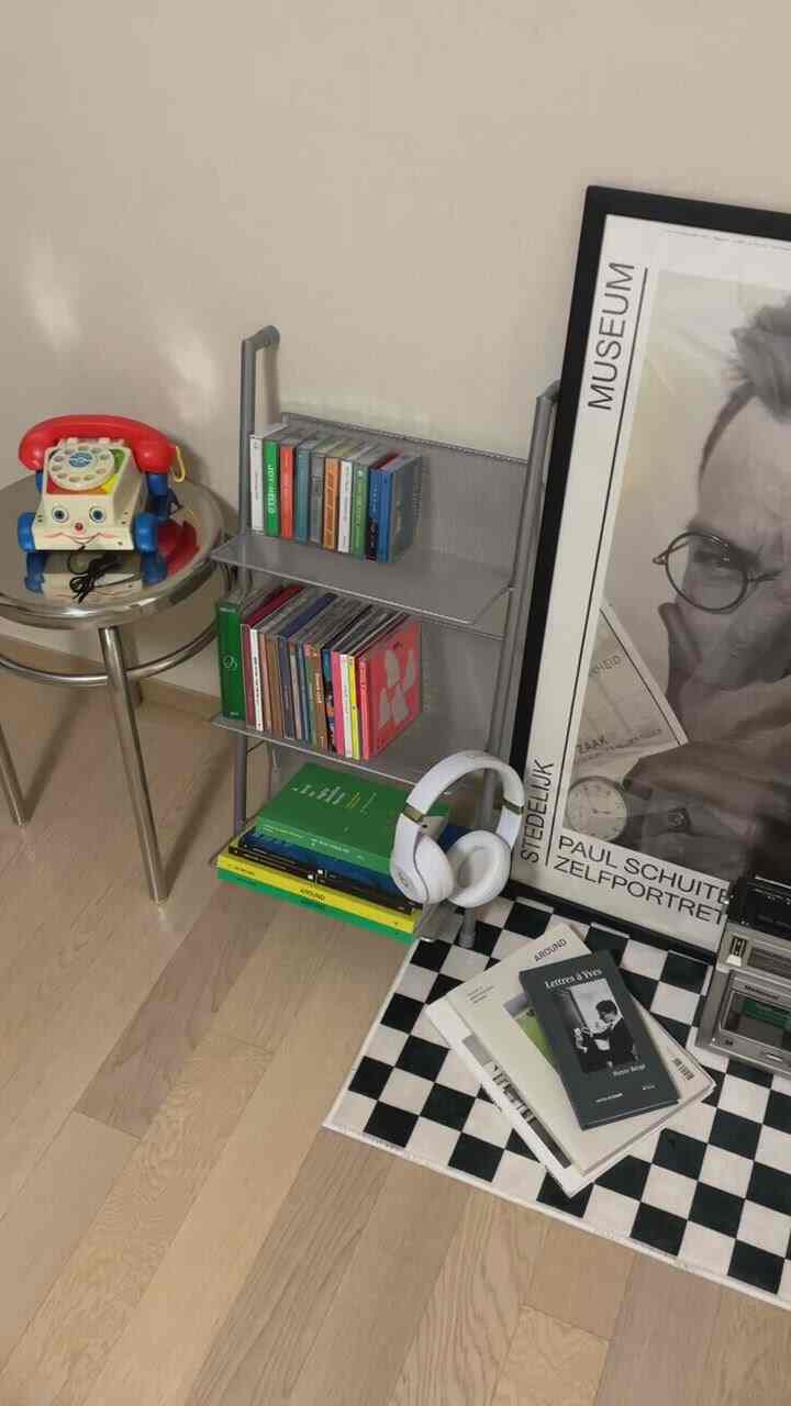 Beige and gray toned compact room featuring a checkerboard rug and metal shelf, a modern space for music and reading enjoyment