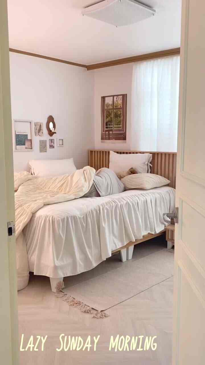 Cozy bedroom with soft white tones and wooden bed frame, flooded with natural light