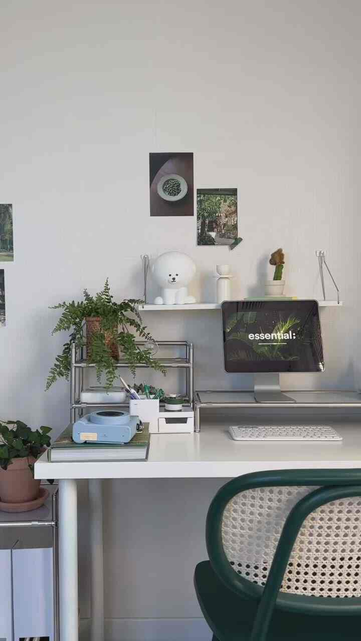 白い壁と机、緑の椅子と植物が配置された清潔感のあるホームオフィス空間