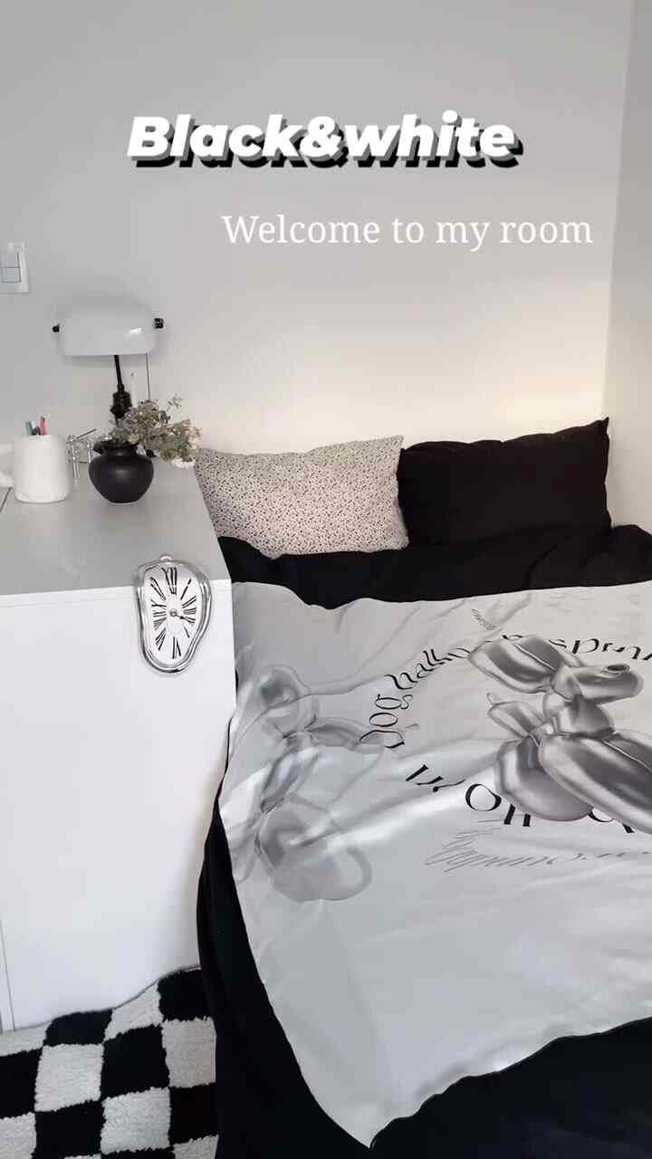 Black and white toned studio bedroom featuring a modern bed with patterned duvet cover and checkered rug creating a clean, stylish space