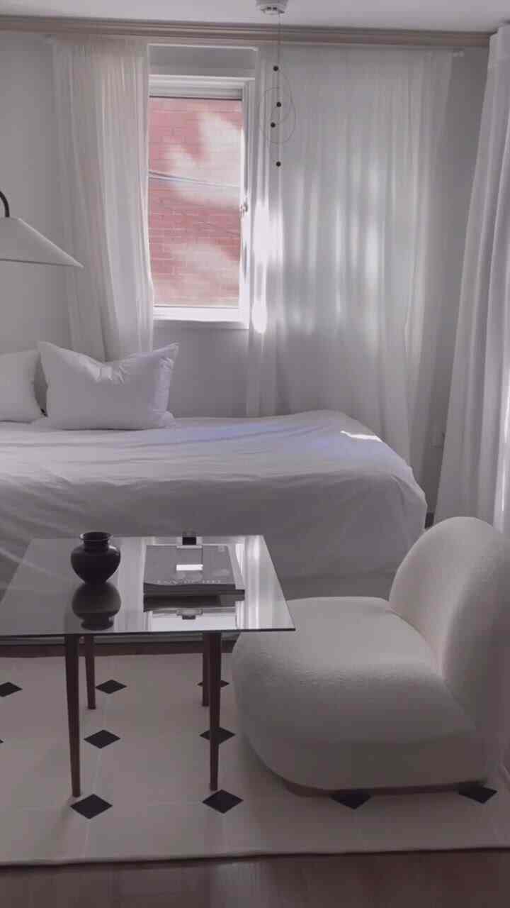 White-toned bedroom featuring a clean modern sofa and glass coffee table with a minimalistic atmosphere