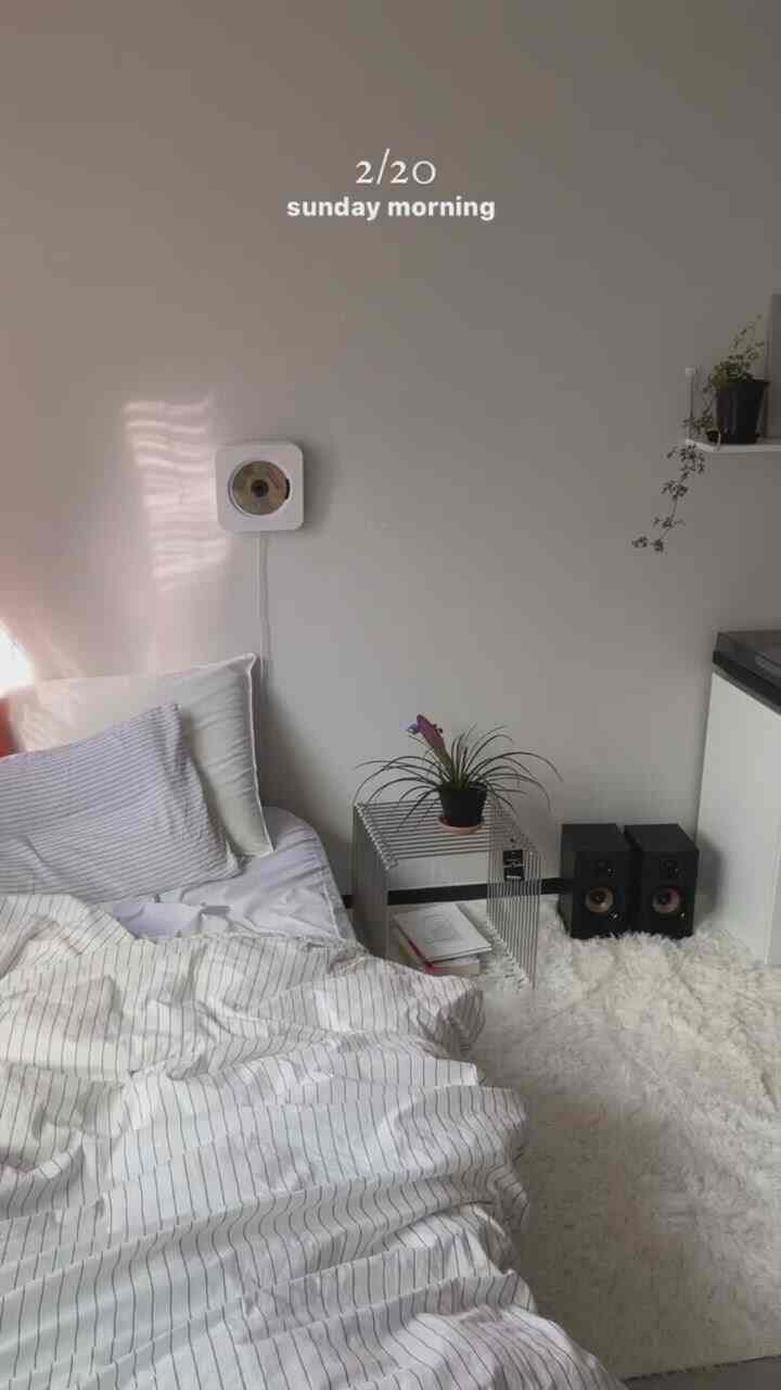 White and natural toned bedroom featuring cozy bedding and a soft rug in a simple layout