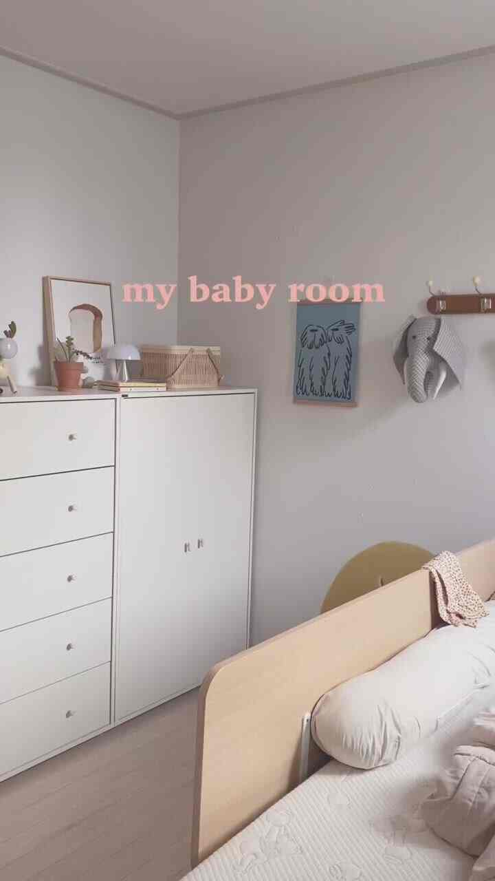 暖かいホワイトとウッドトーンの調和した赤ちゃんの部屋、整然としたドレッサーとベビーベッドが配置された印象的な空間