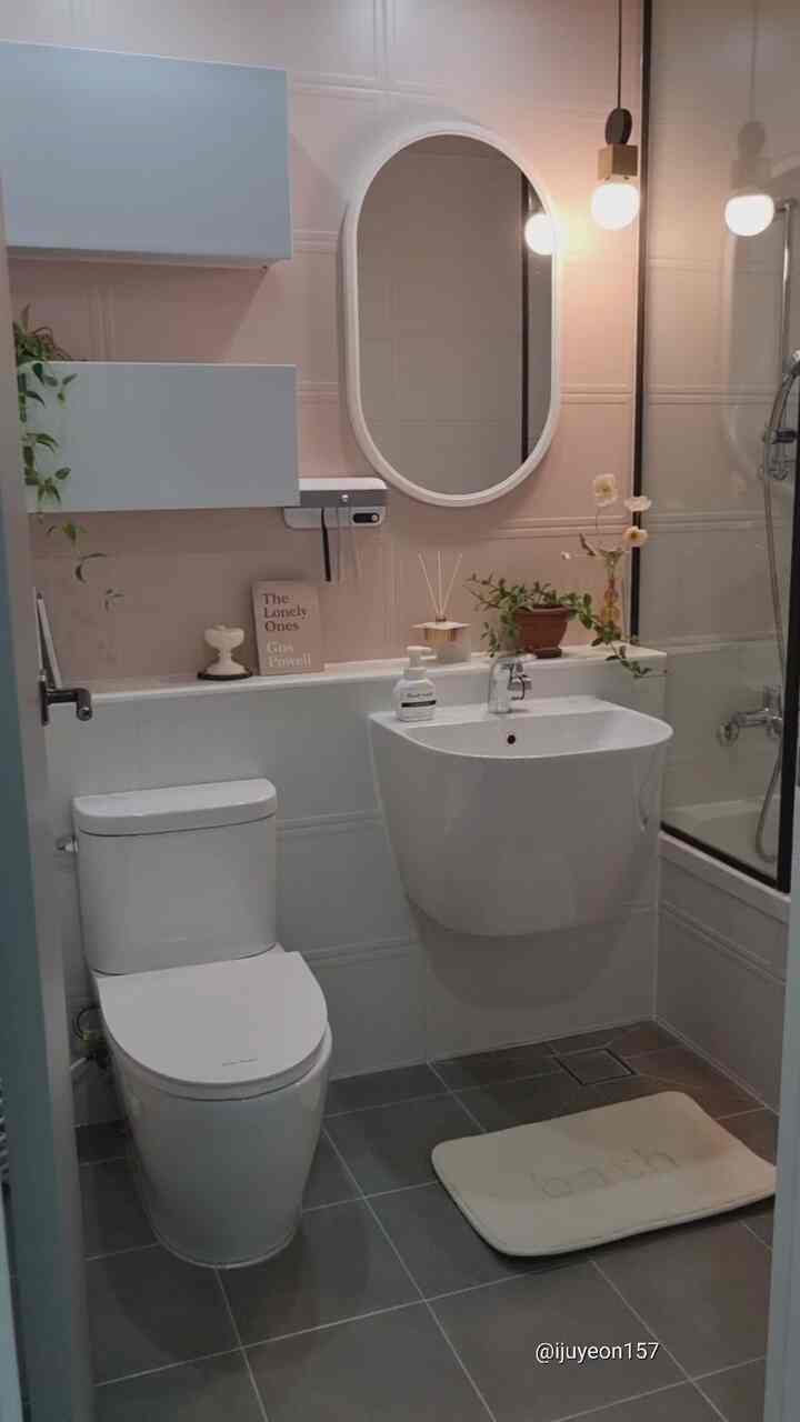 白とグレーの色調のバスルーム、洗練された洗面台とバスマット、植物が配置された自然でシンプルな雰囲気のインテリア