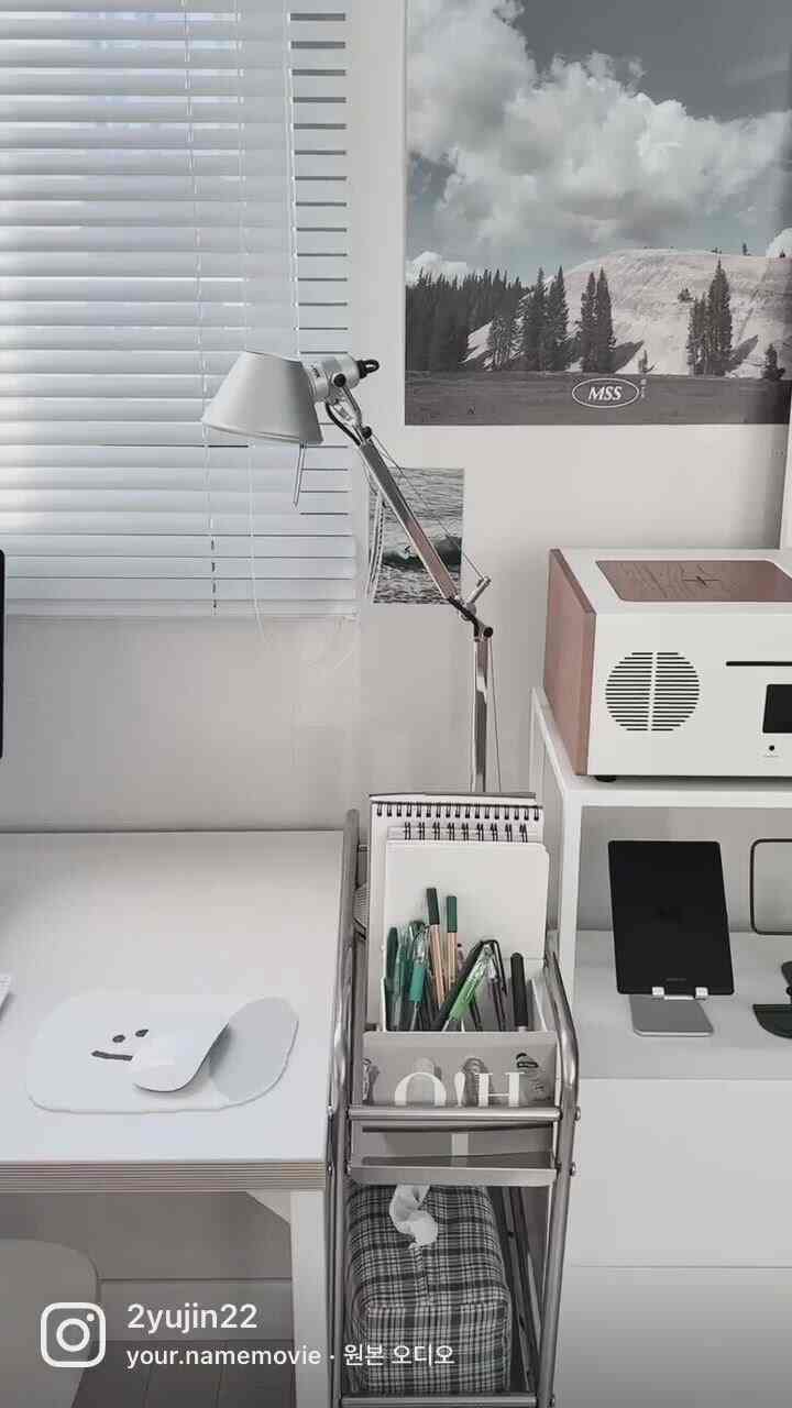 白を基調としたワンルームのデスク、ステンレス製の照明と整理されたシンプルなホームオフィスのインテリア