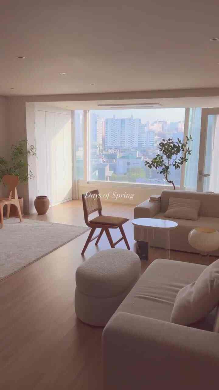 ベージュとホワイトの色調のリビング、自然光が差し込む大きな窓とミニマルな家具が配置されたナチュラルモダンな空間