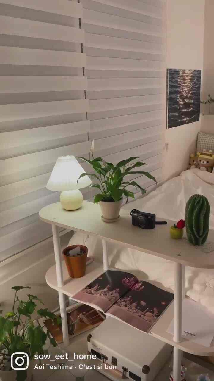 White and natural-toned bedroom featuring plants and a table lamp, creating a cozy atmosphere