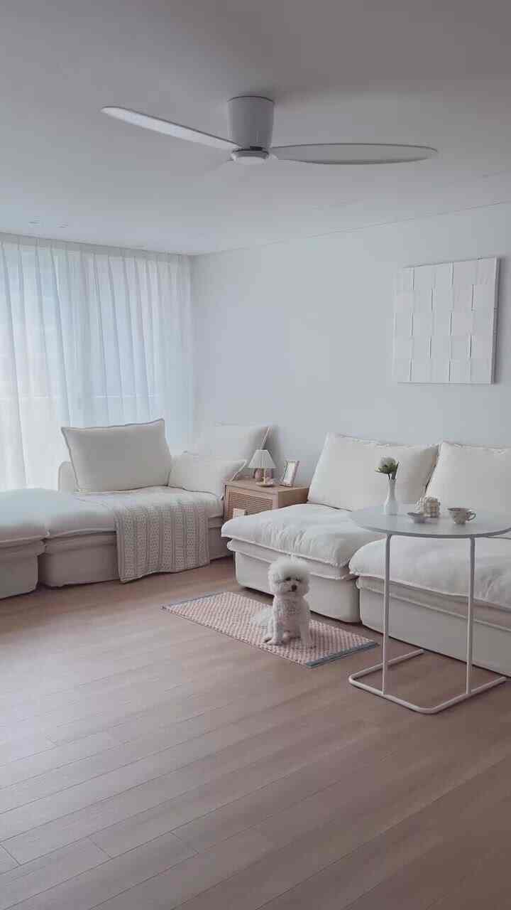 白とウッドトーンが調和したミニマルなリビング、ファブリックソファとシーリングファンが落ち着いた週末の雰囲気を醸し出すインテリア