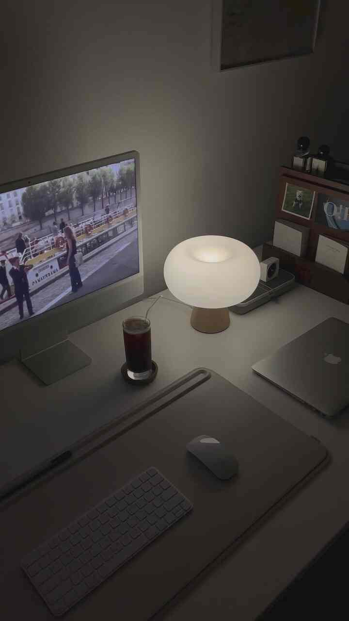 Calm white-toned study featuring an iMac monitor, ambient mood lamp, and a coffee glass on a neat desk.