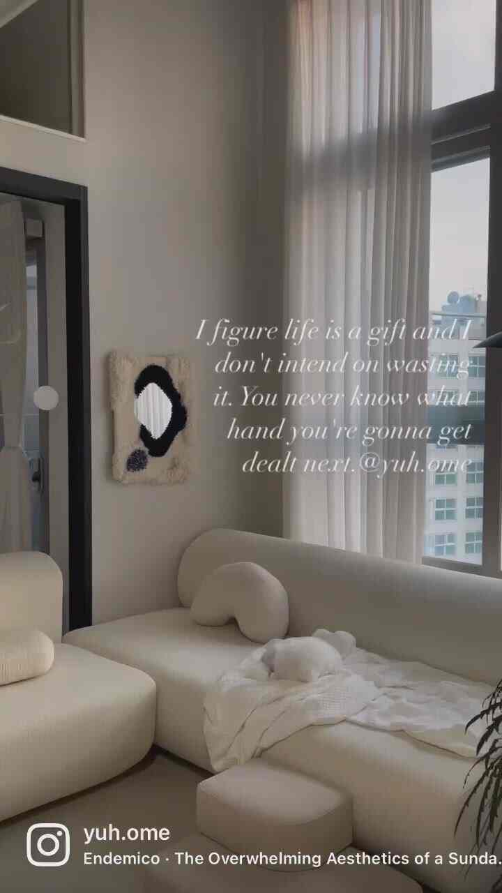 White-toned living room featuring modern sofa and curtains, with a pet sleeping on the sofa creating a cozy atmosphere