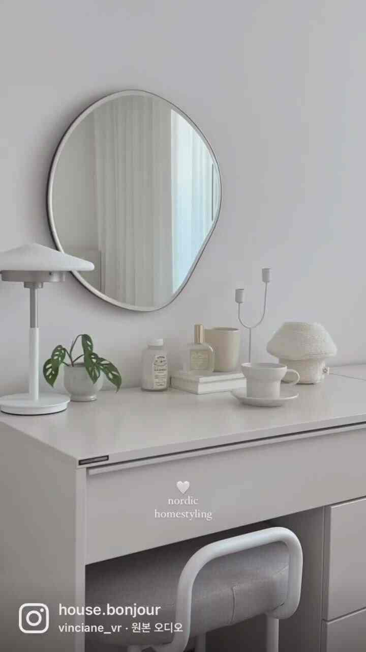 明るいホワイトトーンの北欧スタイルの化粧台、丸みを帯びた不定形の鏡とシンプルな小物が配置された清潔感のある空間