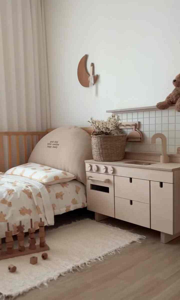 Soft beige and wood-toned baby room featuring a crib and wooden play kitchen, creating a natural and cozy atmosphere