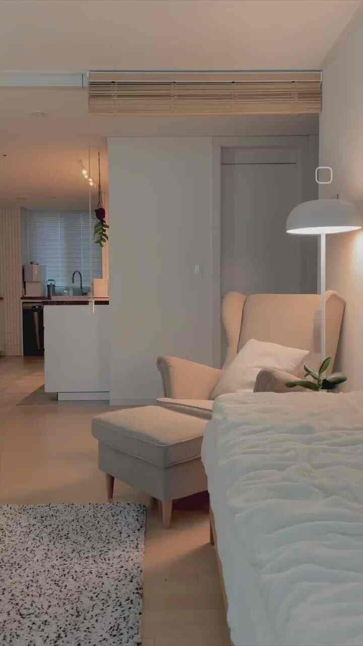 白と木目調が調和するリビングと玄関の空間、ウッドブラインドとアームチェアが配置されたナチュラルモダンなインテリア