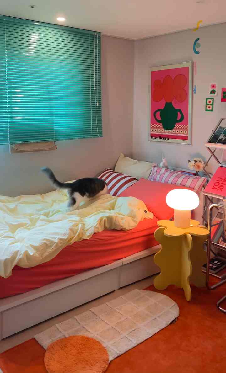 白と木目調が調和する一人寝室、清潔な寝具と猫用品が配置されたミッドセンチュリーモダンの印象的な空間