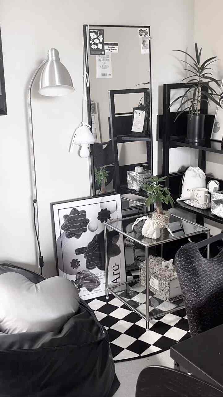 黒と木目調が調和したワンルームのインテリア、金属製の本棚とビーズクッションのソファが配置されたシンプルでモダンな雰囲気の空間