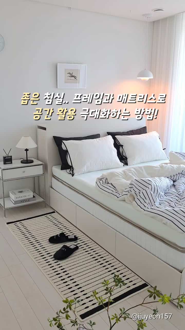 白とナチュラルトーンの狭い寝室、収納付きベッドフレームとシンプルな寝具が配置された雰囲気のあるインテリア