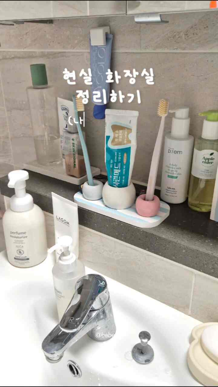 グレー系のバスルーム棚に整頓された透明な収納容器と歯ブラシ立てが配置された清潔感のある空間